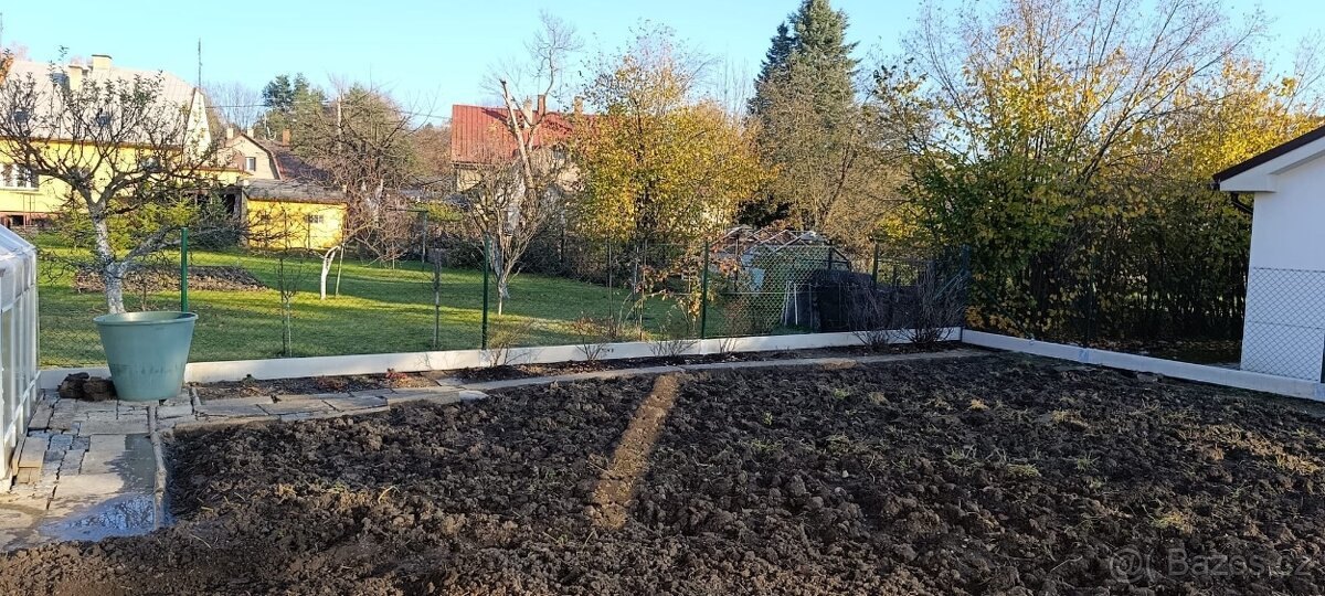 Pletivový plot s bílými podhrabovými deskami po obvodu připravené zahrady