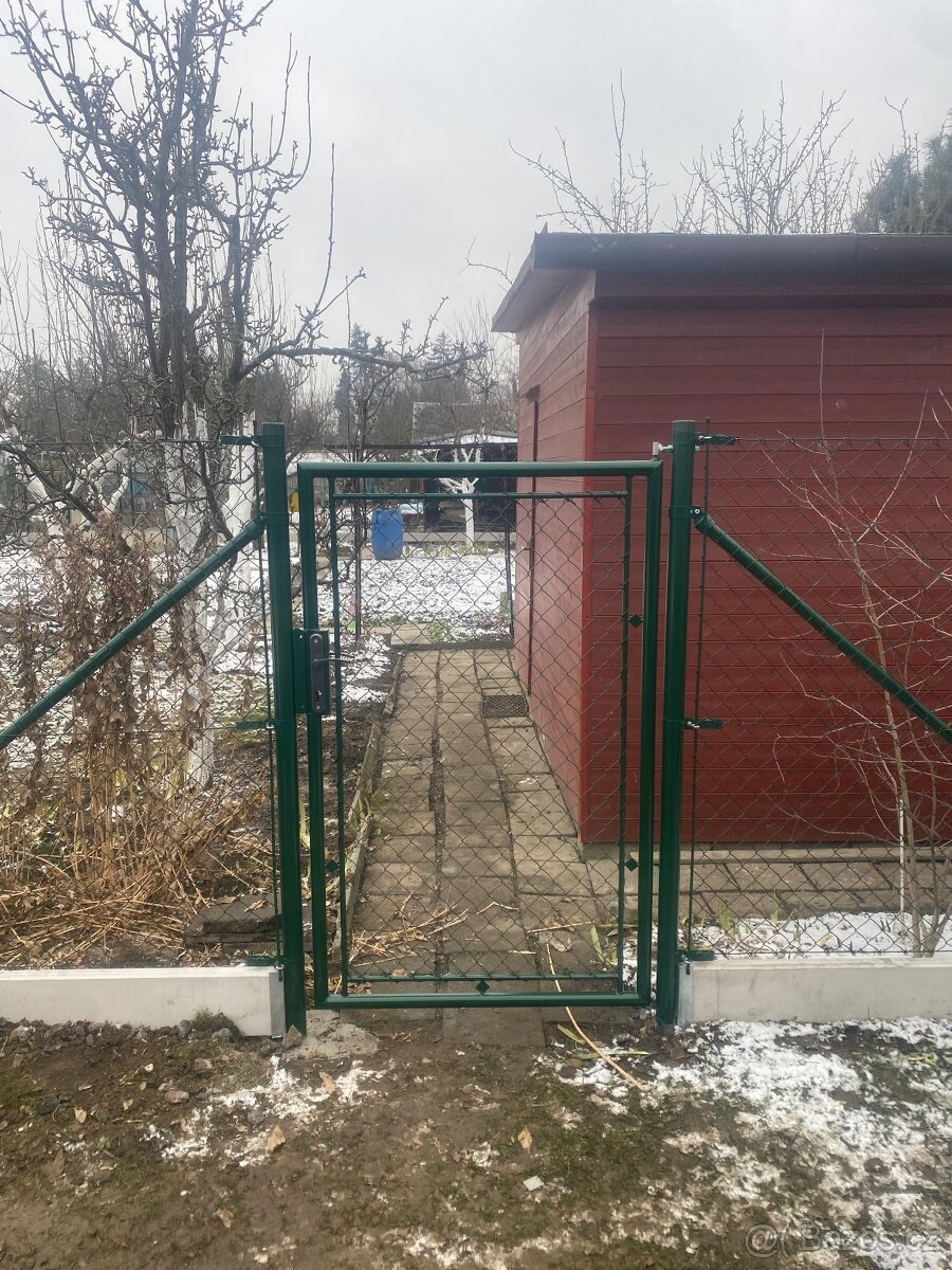 Zelená branka s diagonálními výztuhami a pletivovou výplní na vstupu do zahrady